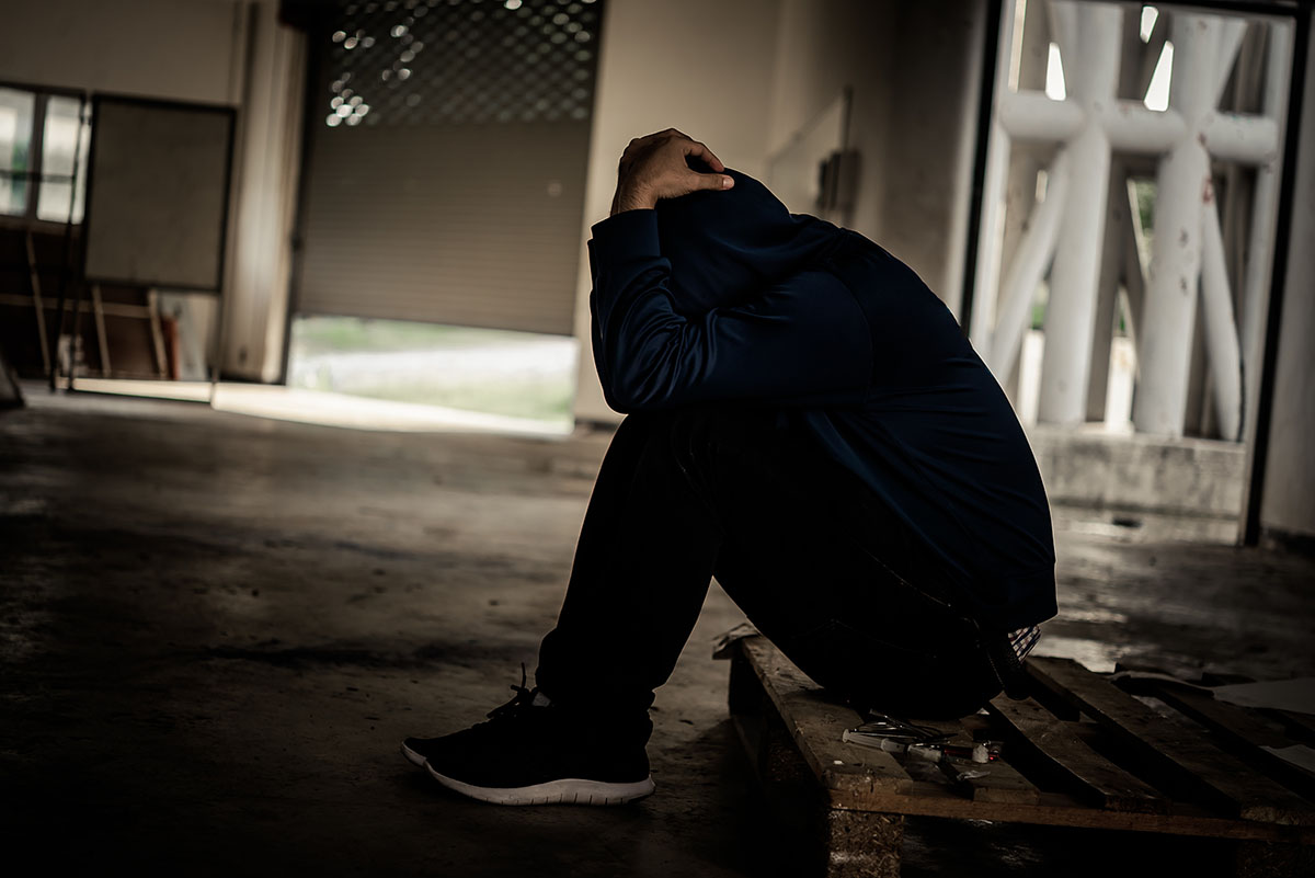 a man sits on the curb as he thinks about heroin overdose symptoms