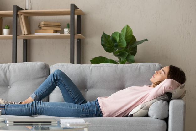 a woman lies on a couch and wonders how to promote good mental health