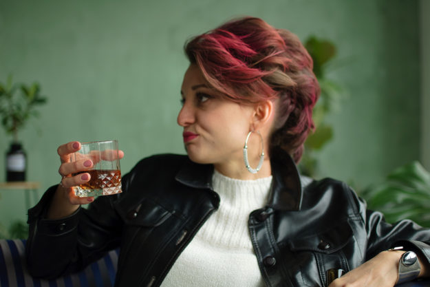a woman with dyed red hair drinks and thinks about the connection between personality and alcohol dependence