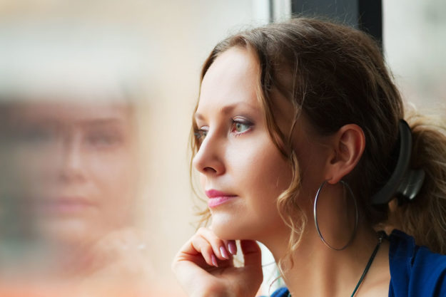 a woman stares out the window as she considers relapse prevention