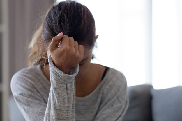 a woman rests her head against her wrist as she struggles with the signs of anxiety