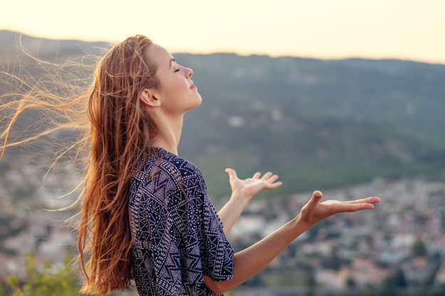 a young woman lifts her hands to celebrate having a support system for recovery