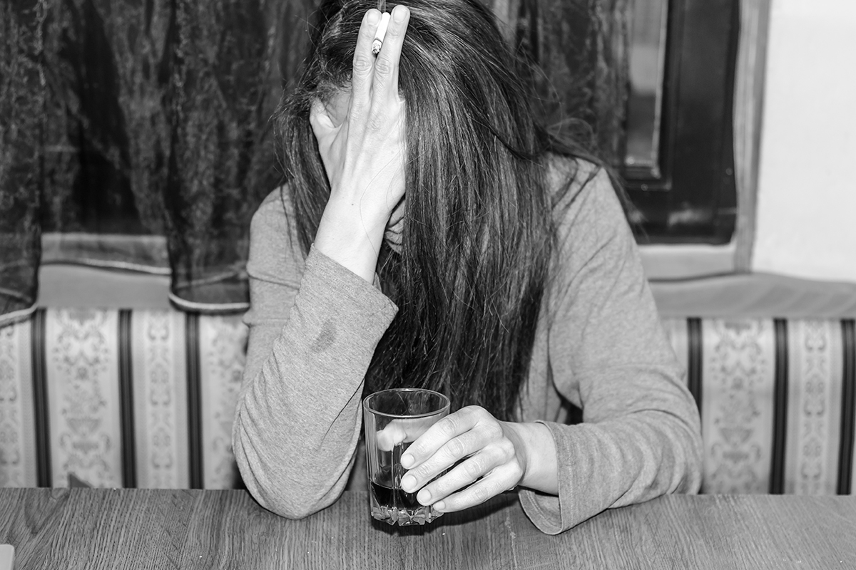 a woman drinks as she considers the ramifications of women and alcoholism