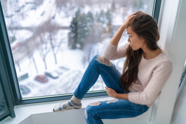 a young woman looking at the snow thinking about seasonal depression