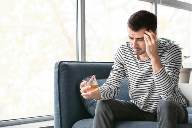 a man looking at his glass thinking about Signs of Alcoholism